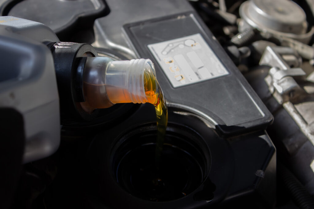 a car engine with a fluid being poured into a container